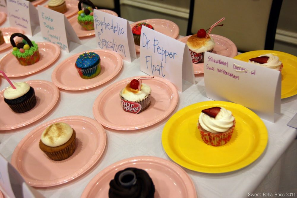 different types of cupcakes on pink plates lined up on a white table