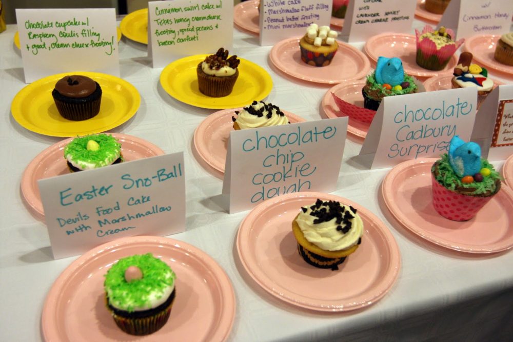 different flavors of cupcakes on pink plates with name tags
