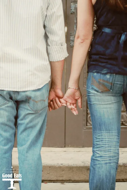 man and woman holding pinky fingers take from behind