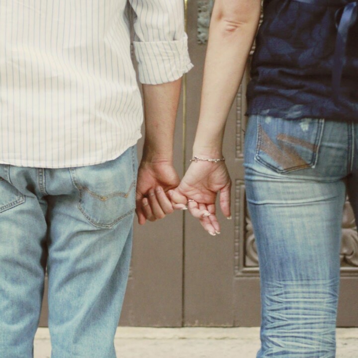 man and woman holding pinky fingers taken from behind