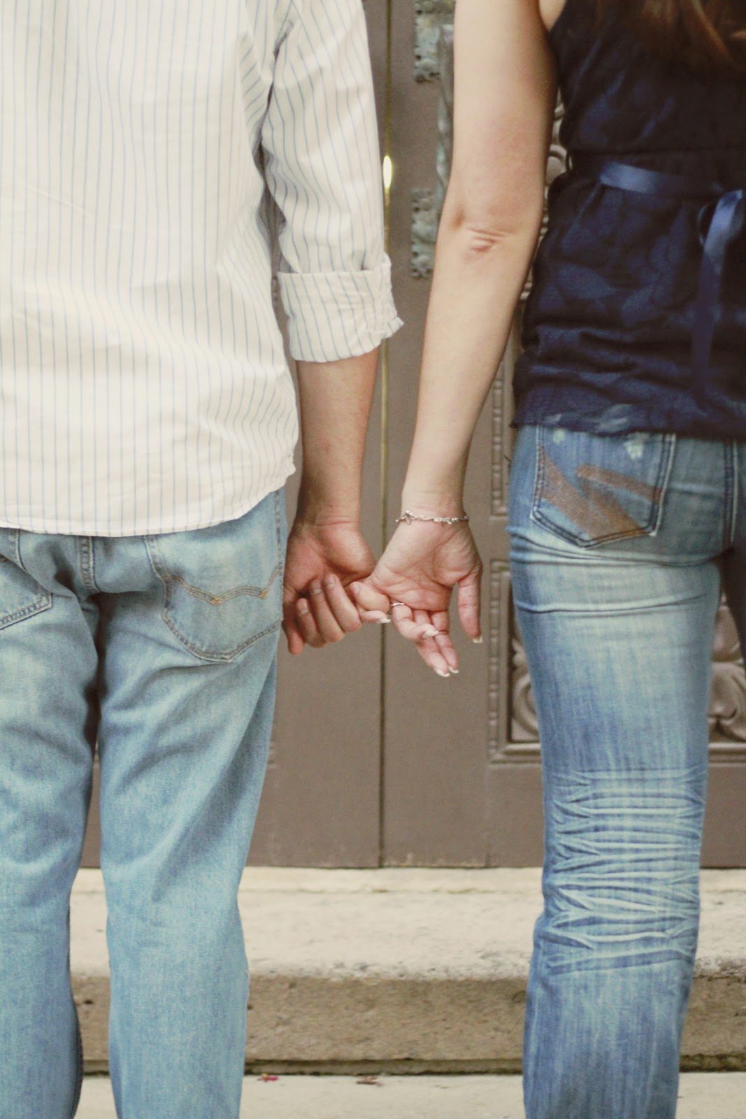 man and woman holding pinky fingers taken from behind