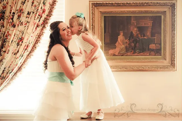 flowergirl kissing bride on the cheek