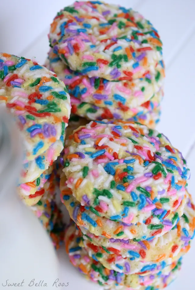 Three tall stacks of confetti cookies next to a pitcher of milk. 