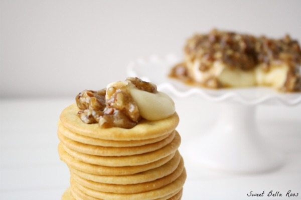 A stack of crackers topped with pecan brie cheese. 