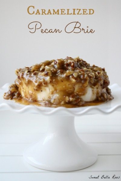 A pecan brie appetizer on a small white cake stand. 