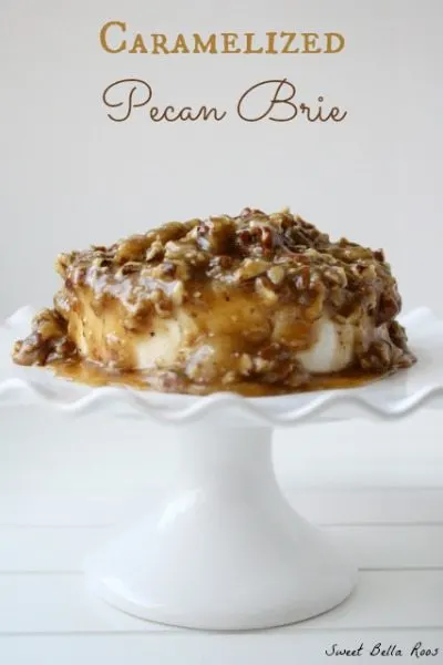 A pecan brie appetizer on a small white cake stand.