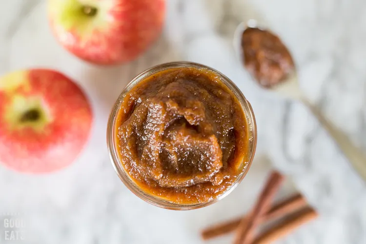 jar of pumpkin apple butter next to apples and cinnamon sticks