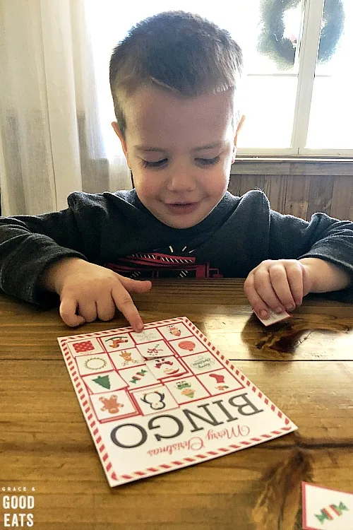 little boy sitting at a table playing Christmas bingo