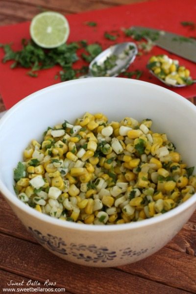 copycat chipotle corn salsa in a white bowl. cilantro and lime is in the background.