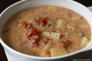 bowl of crockpot cheeseburger soup with chunks of potatoes, ground beef, and diced tomatoes