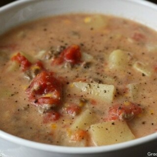bowl of crockpot cheeseburger soup with chunks of potatoes, ground beef, and diced tomatoes