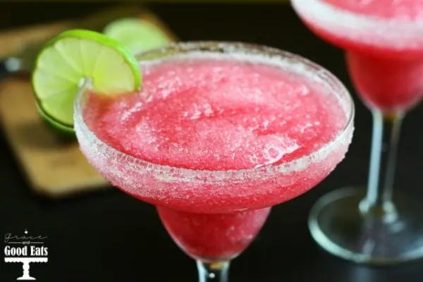bright red cranberry margarita in a clear glass with salt and lime on the rim