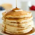 perfect pancakes on a plate with berries in the background