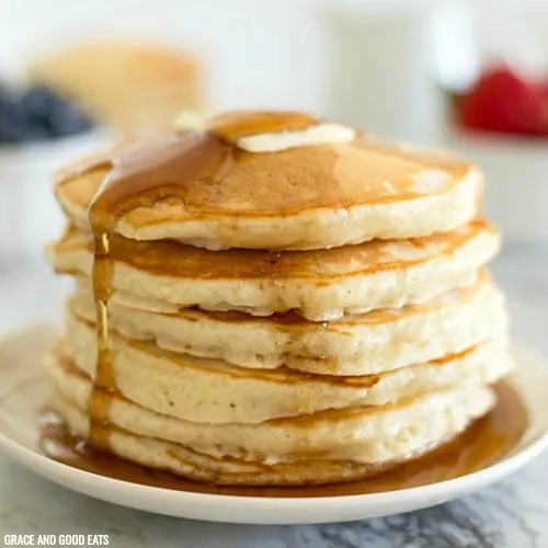 golden, fluffy pancakes with a pat of butter on top and syrup cascading down