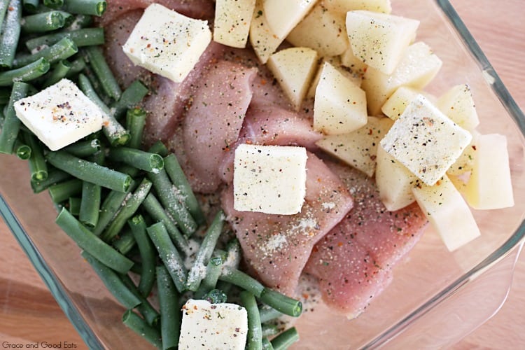 casserole dish with green beans, chicken, and potatoes topped with butter