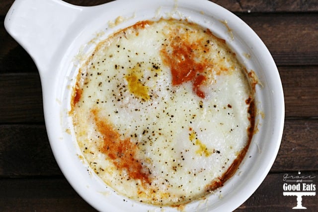 overhead shot of a white bowl with eggs, marinara, and cheese