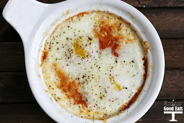 overhead shot of a white bowl with eggs, marinara, and cheese
