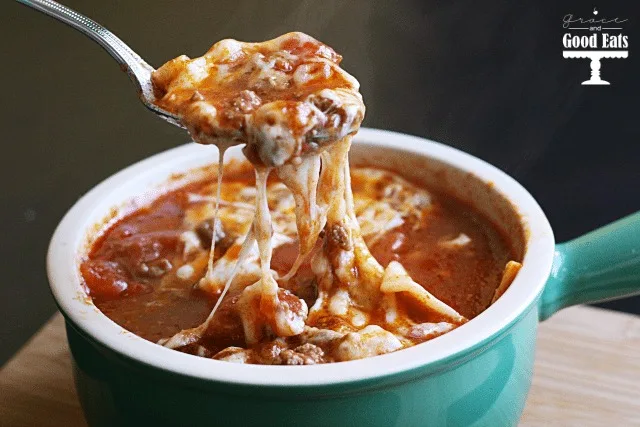a portion of cheesy lasagna soup being spooned from a soup dish 