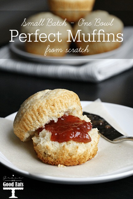 A plain muffin slathered with jam on a white plate. 