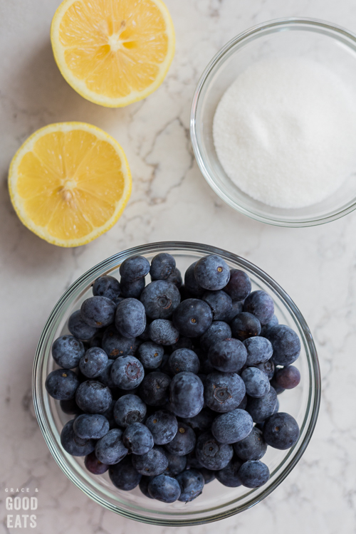 bowl of blueberries, bowl of sugar, and a lemon cut in half
