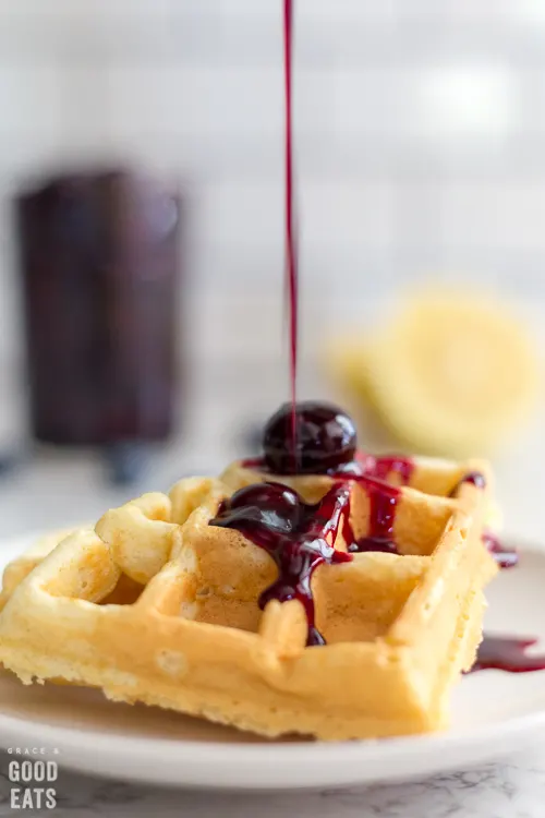 blueberry syrup drizzled over waffles on a plate