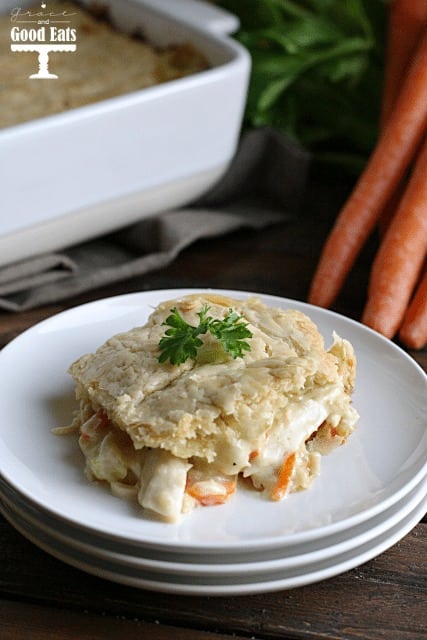 a portion of chicken pot pie with pie crust on a stack of white plates 