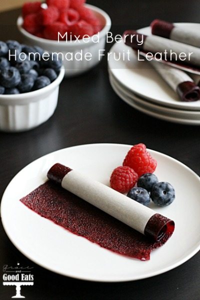 a homemade fruit leather on a white plate with a couple fresh berries 