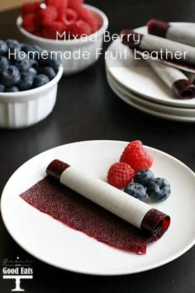 a homemade fruit leather on a white plate with a couple fresh berries