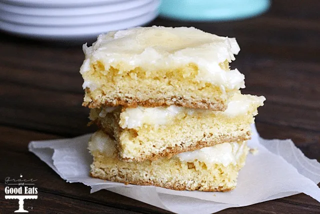 three ooey gooey butter cake bars stacked on squares of parchment paper 