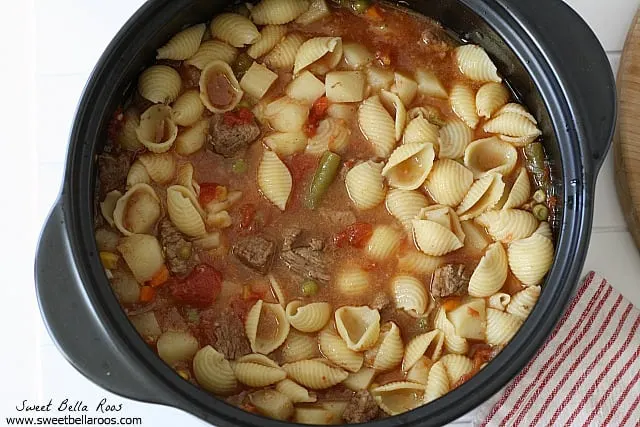 overhead view of vegetable soup with meat in a large pot. 