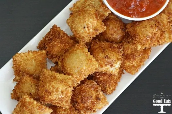 overhead view of fried cheese ravioli on a white tray with a dish of marinara on the side