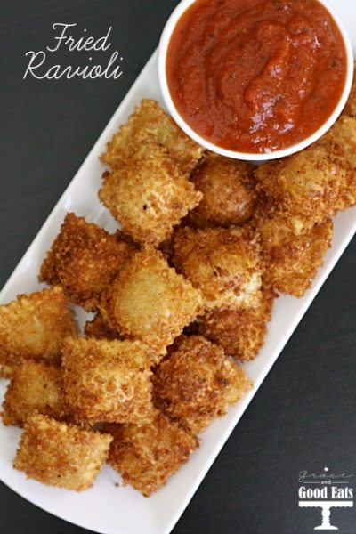 fried ravioli on a white tray with a bowl of marinara sauce