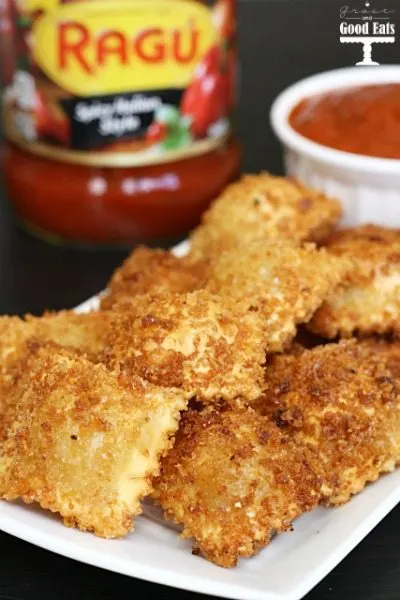 fried cheese ravioli on a white tray with marinara sauce in the background 