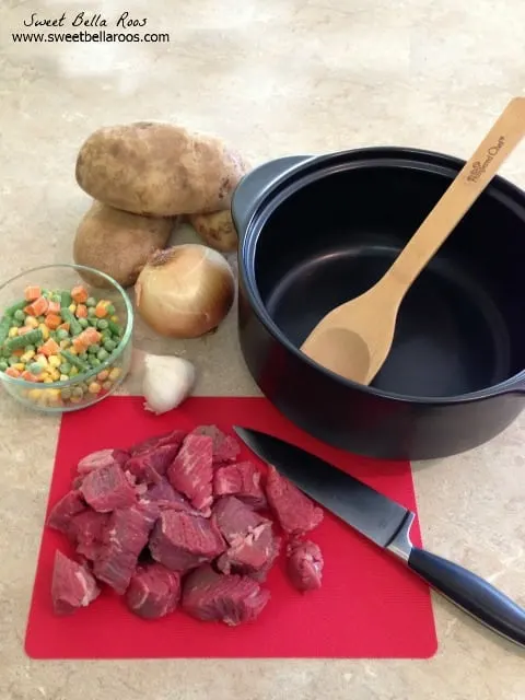 ingredients for beef and vegetable soup next to an empty pot. 