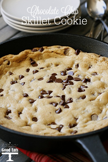 chocolate chip skillet cookie on red tea towel next to stack of plates