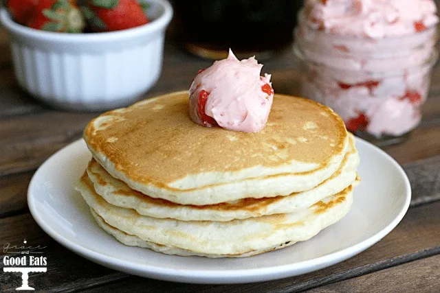 stack of pancakes topped with pat of strawberry butter