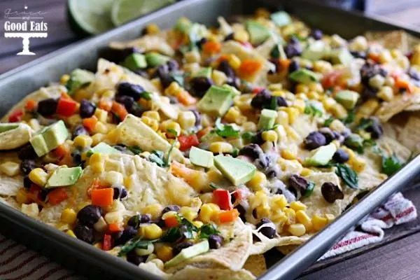 four cheese nachos with black beans, corn, peppers, and avocados