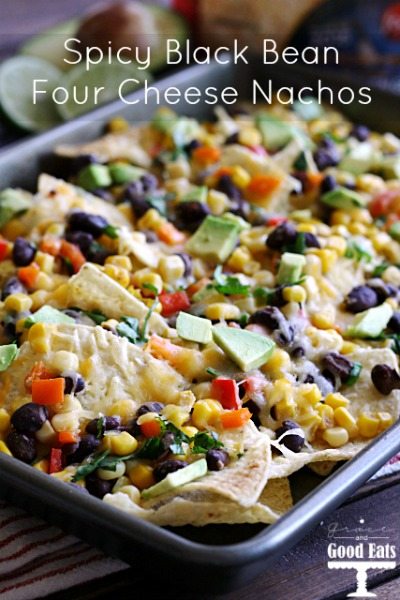 sheet pan full of tortilla chips with black beans, cheese, corn, peppers, and avocados