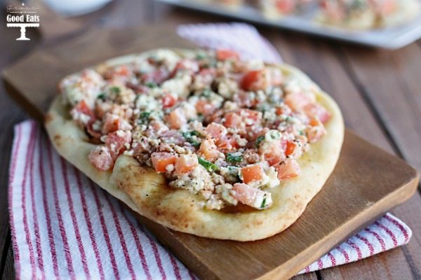 flatbread dough topped with tomatoes, feta, and Greek seasoning