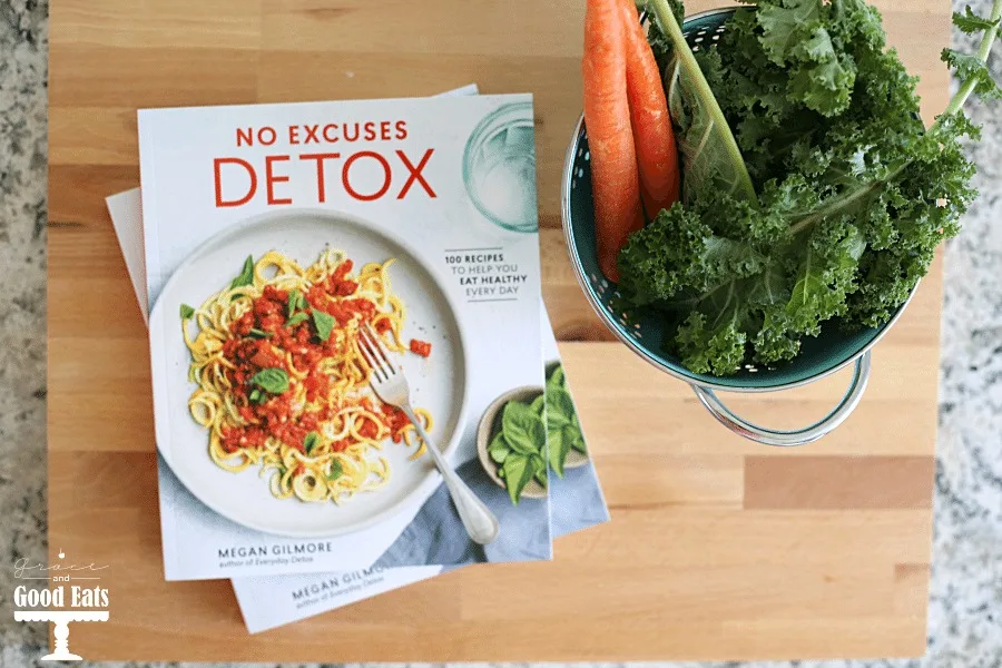 Overhead view of No Excuses Detox cookbook, carrots, and kale. 