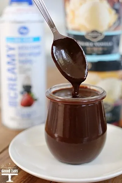 Mexican chocolate sauce in a glass jar. A spoon dangles over the glass. 