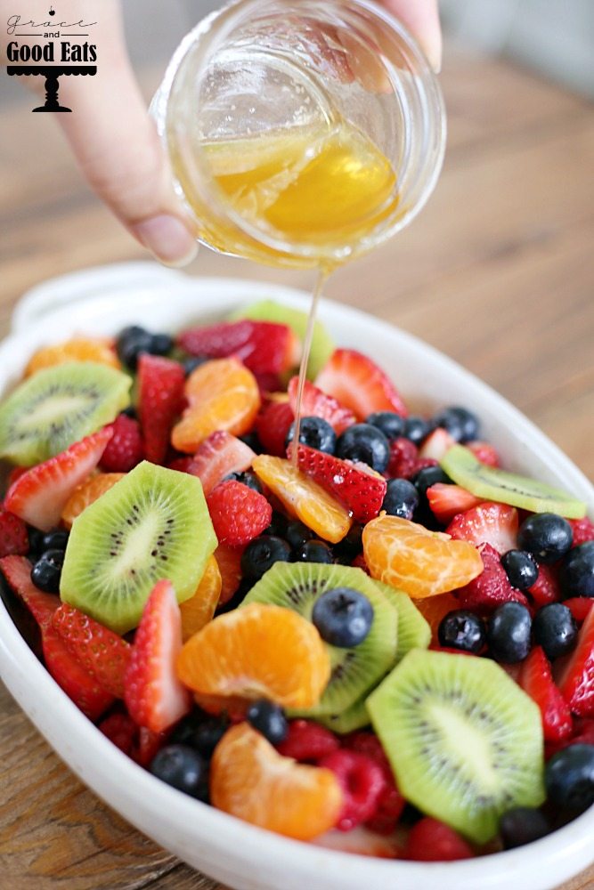 frizzling honey lime dressing over dish of fruit salad