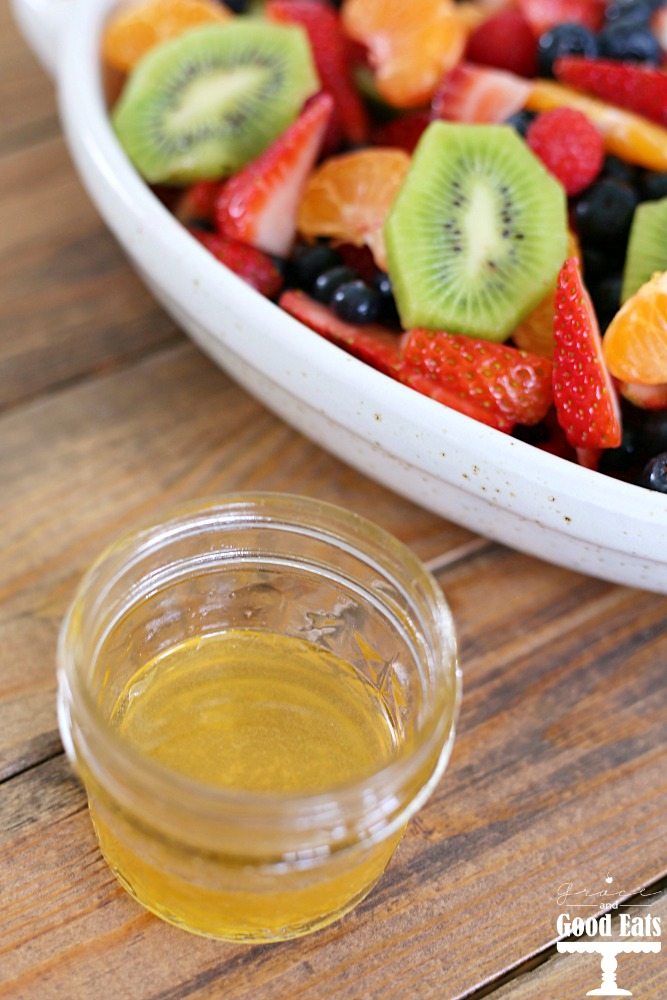 bowl of fruit salad next to container of fruit salad dressing