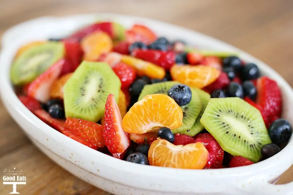 white dish of fruit salad with honey lime dressing