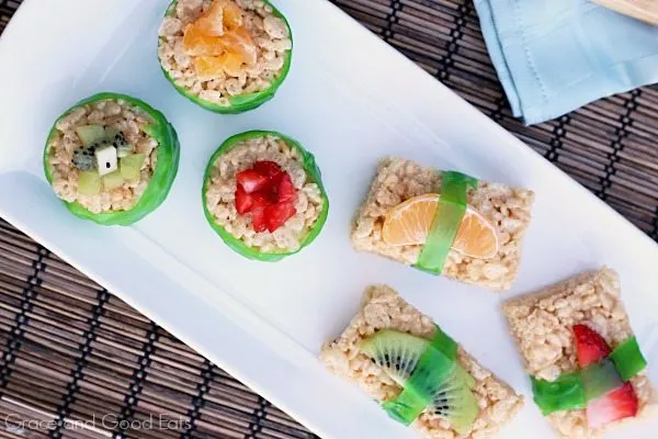 round rice krispie treats on a plate wrapped in fruit leather and topped with fresh kiwi and strawberries