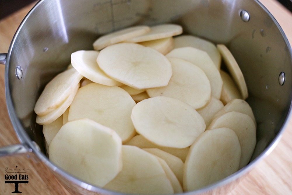 large stockpot full of thinly sliced potatoes