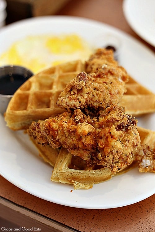 chicken and waffles with a fried egg on a large white plate