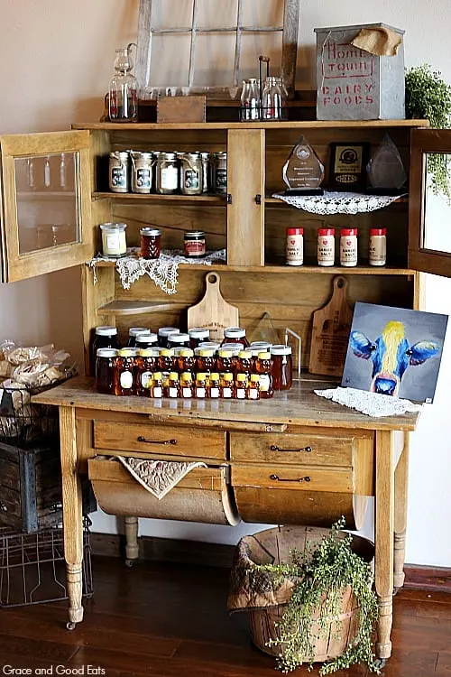 wooden hutch filled with goodies for sale like honey, seasonings, and spices