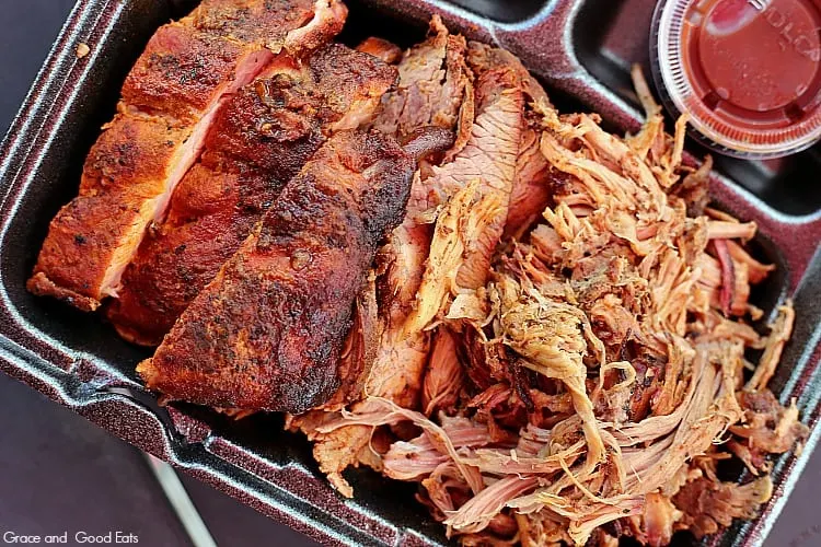 BBQ ribs, tri tip, and pulled pork on a black to-go container