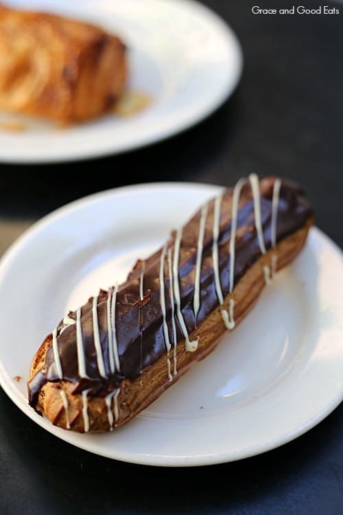 chocolate eclair with an icing drizzle on a plate